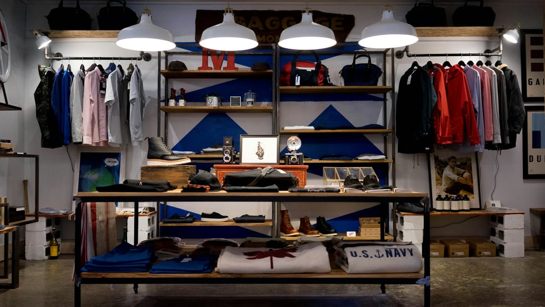Shopify Store Development - a menswear shop interior with rails of shirts and jackets and a display table of knitwear